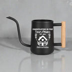 Black gooseneck watering can with wood handle. The design on the side is of a house with botanical accents in white vinyl and the words 'congratulations on your new house' above the design and the  names of the new home owners below the design.