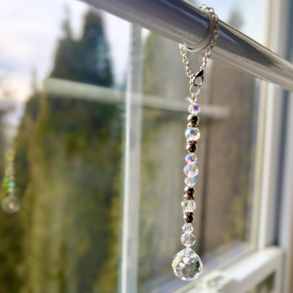 A crystal suncatcher with clear crystal beads hanging from a sun drenched window.