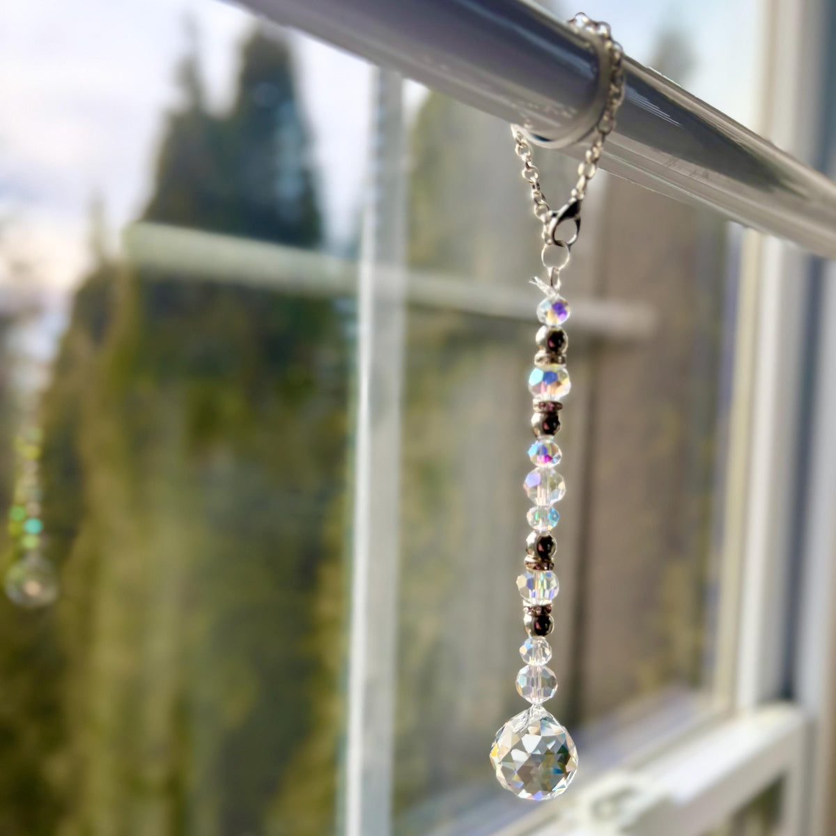 A crystal suncatcher with clear crystal beads hanging from a sun drenched window.