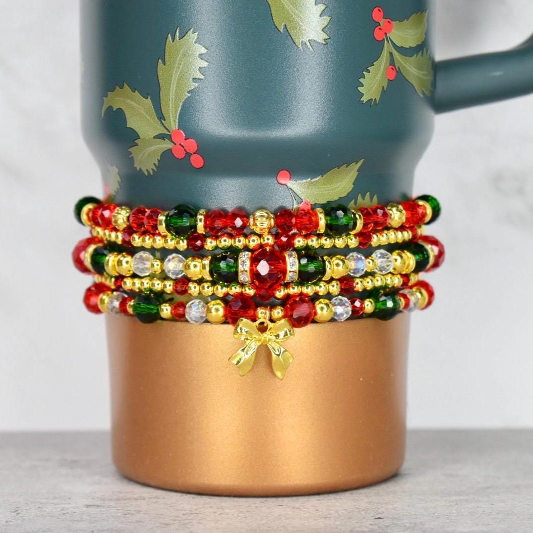 Handmade Holiday Botanical bracelet stack with red green and fold beaded strands and holly charm, styled on a festive holiday tumbler