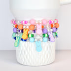 A set of 5 pastel beaded bracelets in pink, orange, purple, green and blue. Each bracelet features a PEEPS bunny charm that matches each of those colors.