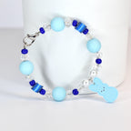 A light blue beaded bracelet with a silver clasp. The bracelet features light blue round beads, clear crystal beads, and dark blue accent beads. A light blue bunny charm hangs from the bracelet.