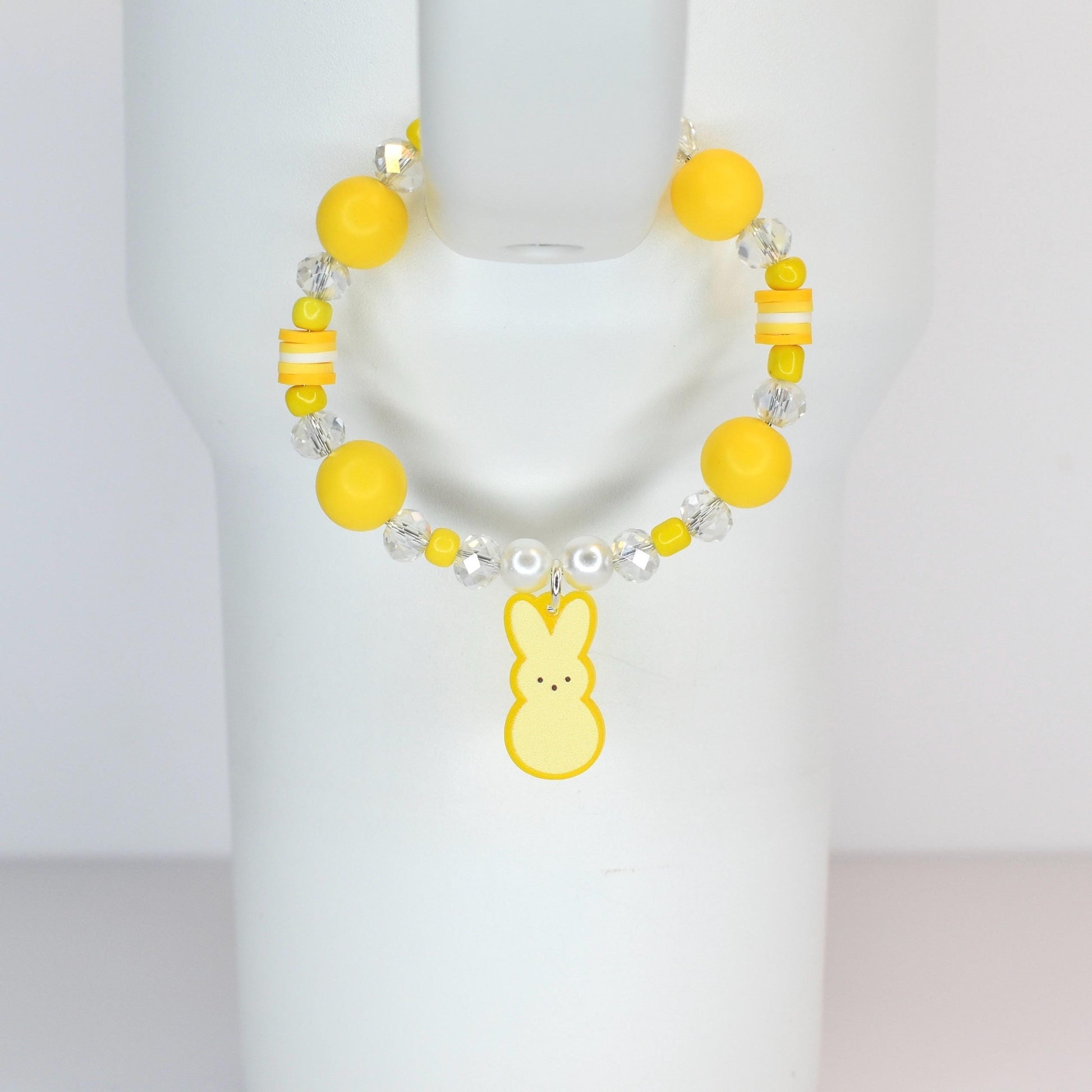 A yellow beaded bracelet with a bunny charm. The bracelet features large yellow beads, clear crystal beads, and a yellow bunny charm. The bracelet is displayed on a white surface.