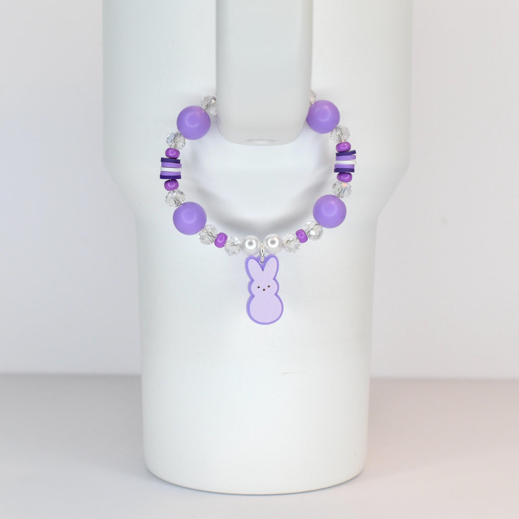 A purple beaded bracelet with a bunny charm. The bracelet features large round purple beads, smaller clear and purple beads, and a dangling purple bunny charm. The bracelet is designed to be worn on the wrist.