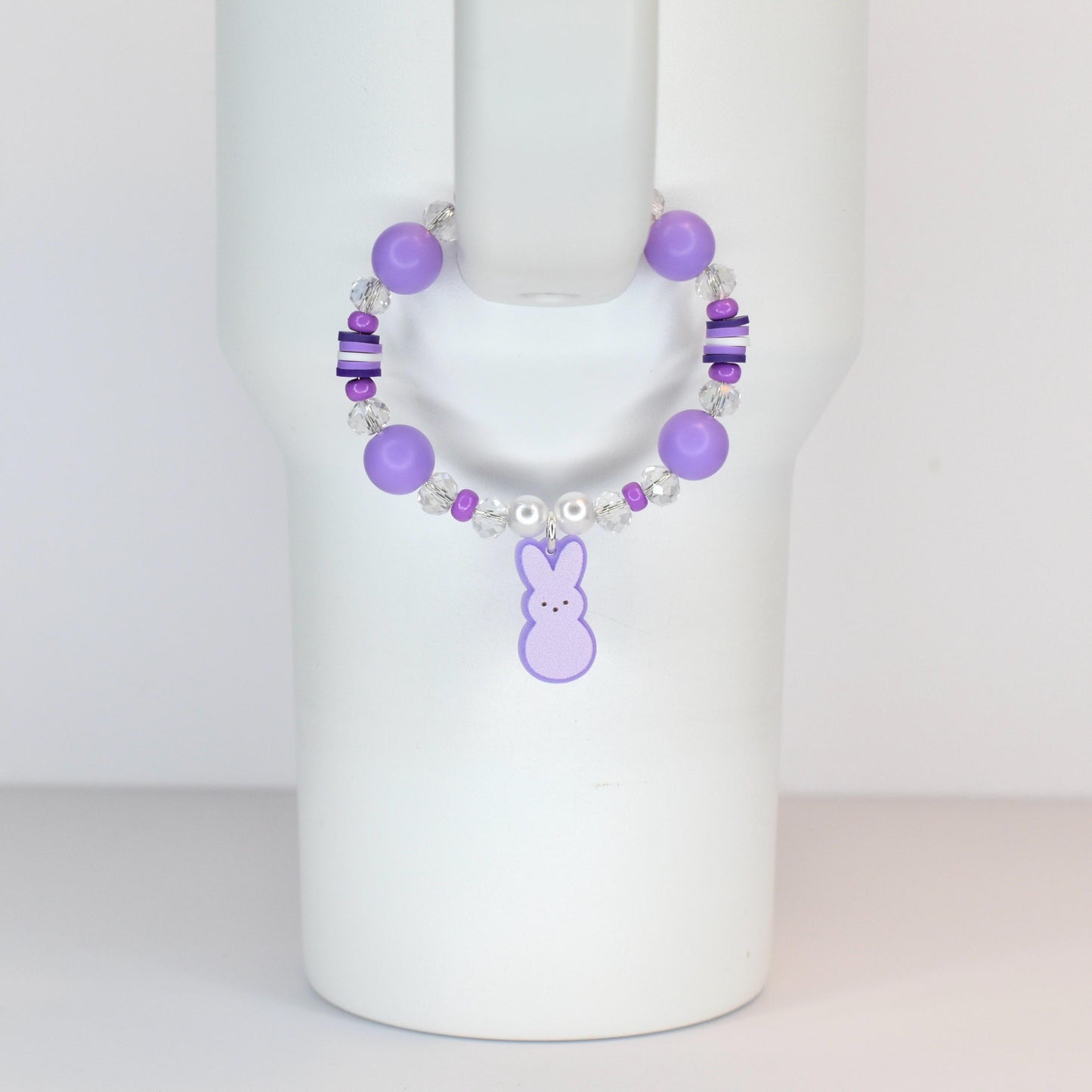 A purple beaded bracelet with a bunny charm. The bracelet features large round purple beads, smaller clear and purple beads, and a dangling purple bunny charm. The bracelet is designed to be worn on the wrist.