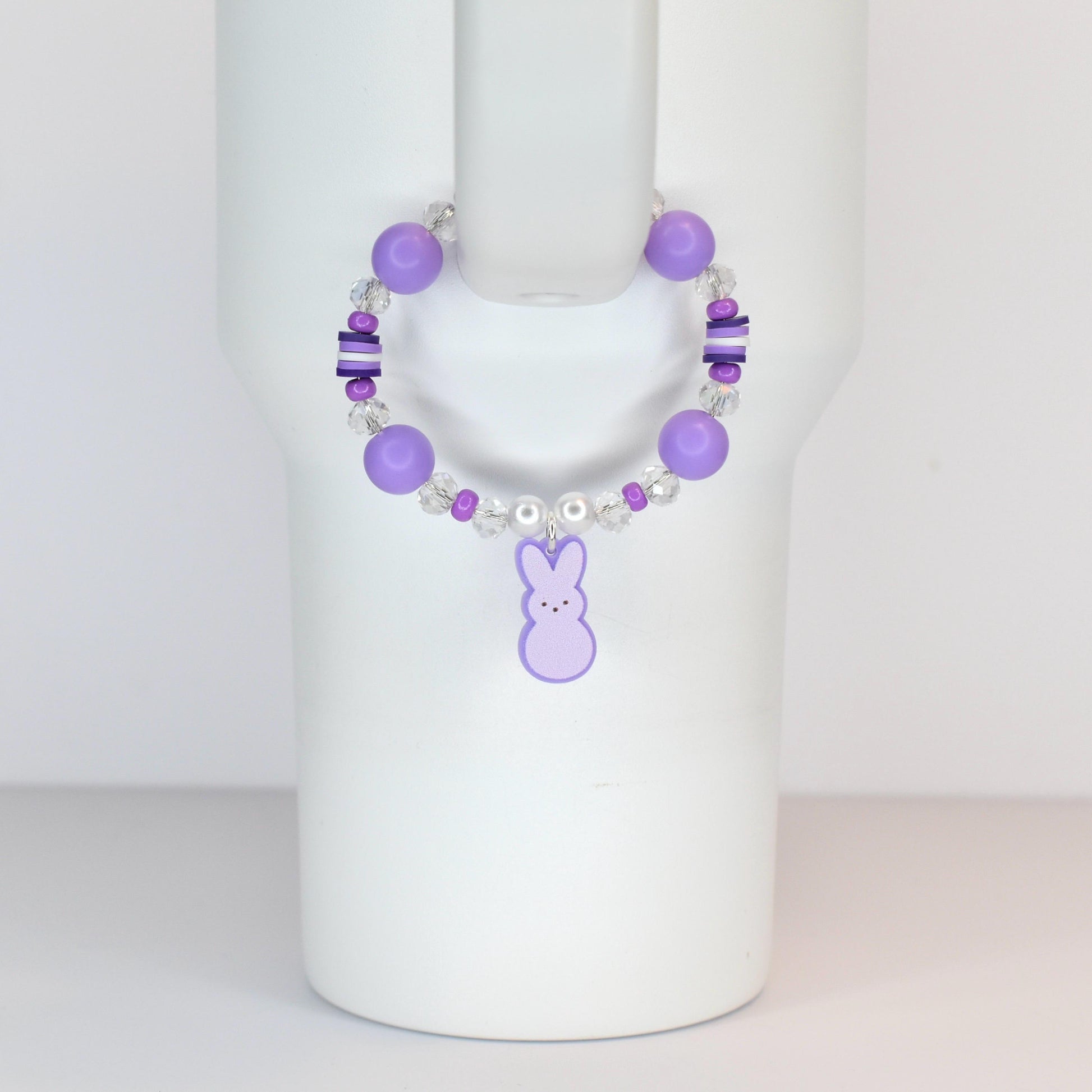 A purple beaded bracelet with a bunny charm. The bracelet features large round purple beads, smaller clear and purple beads, and a dangling purple bunny charm. The bracelet is designed to be worn on the wrist.