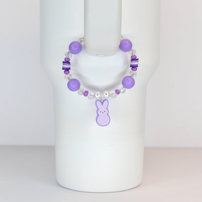 A purple beaded bracelet with a bunny charm. The bracelet features large round purple beads, smaller clear and purple beads, and a dangling purple bunny charm. The bracelet is designed to be worn on the wrist.