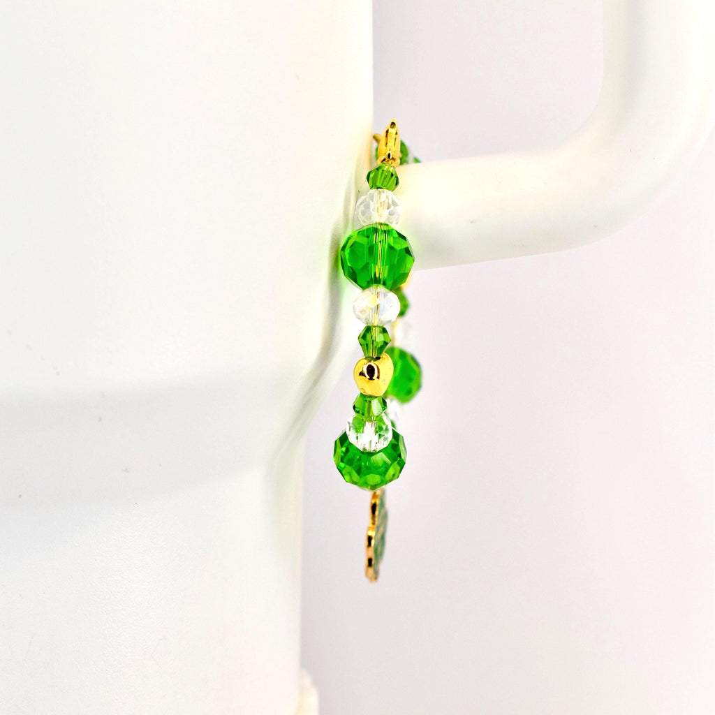 A beaded bracelet with green and clear crystal beads and gold accents. The bracelet features large, faceted green beads, smaller clear beads, and gold-colored metal spacers. A gold charm hangs from the bottom.