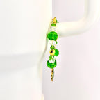 A beaded bracelet with green and clear crystal beads and gold accents. The bracelet features large, faceted green beads, smaller clear beads, and gold-colored metal spacers. A gold charm hangs from the bottom.
