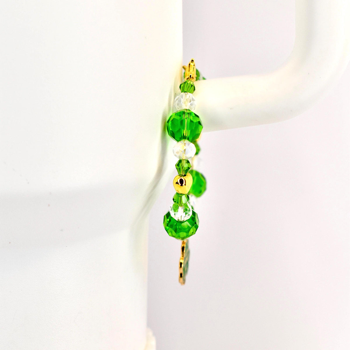 A beaded bracelet with green and clear crystal beads and gold accents. The bracelet features large, faceted green beads, smaller clear beads, and gold-colored metal spacers. A gold charm hangs from the bottom.