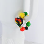 A beaded bracelet featuring a heart-shaped charm with the African continent in black, yellow, red, and green. The bracelet includes yellow, green, red, and black beads. The bracelet is accented with gold-colored metal.
