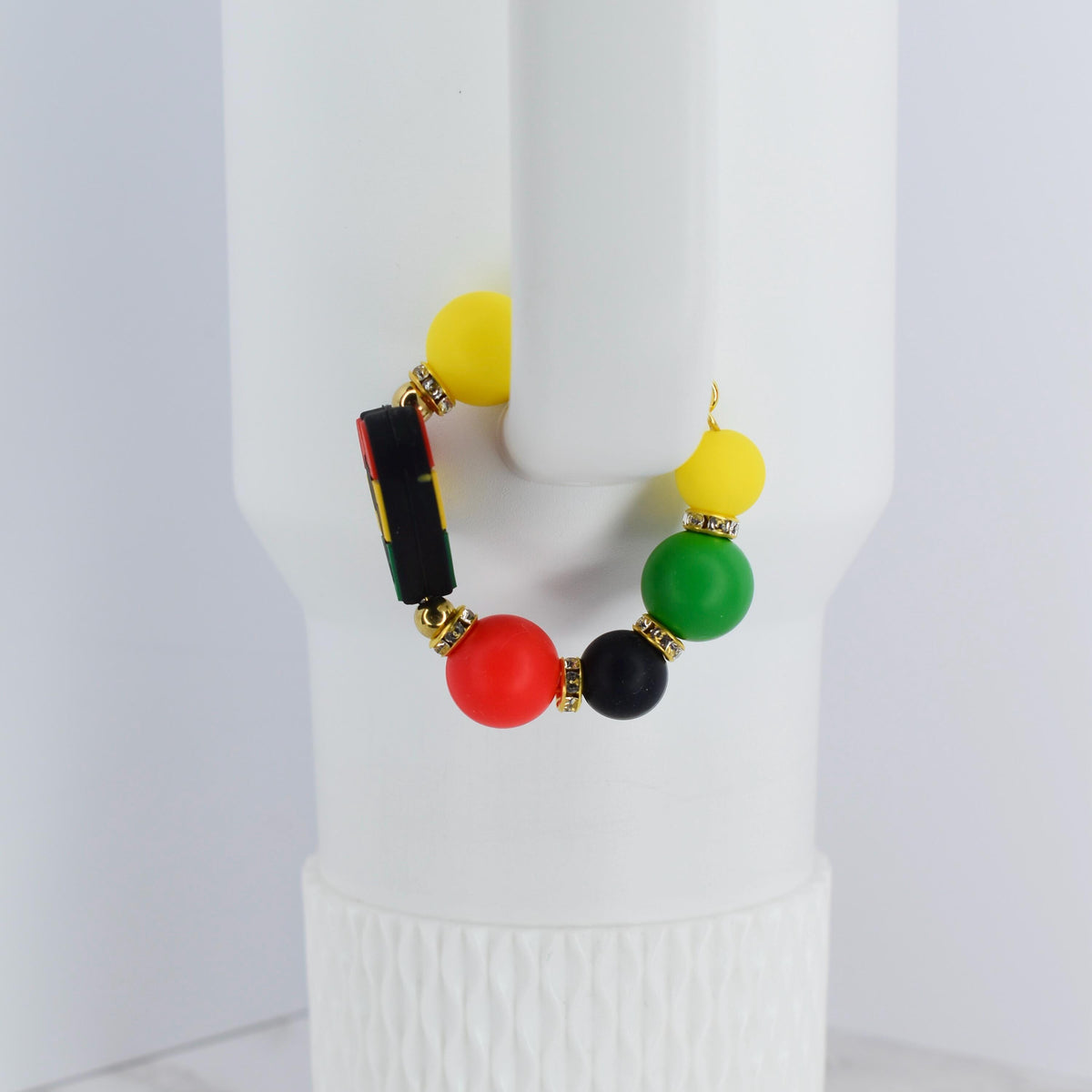 A beaded bracelet with yellow, green, red, and black beads. The bracelet has gold-colored accents and a black bead with a colorful design. The bracelet is displayed on a white background.