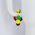 A Stanley handle bracelet featuring a gold-colored chain and colorful beads. The bracelet has yellow, green, black, and red beads. The bracelet is attached to a white surface. The bracelet has a tag with text.