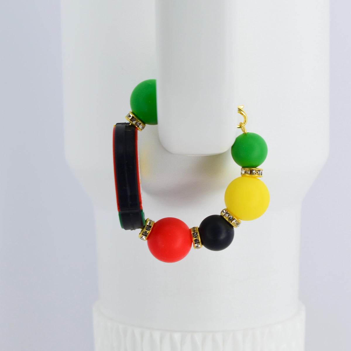 A colorful handle bracelet with a gold-colored hook. The bracelet features a combination of green, yellow, red, and black beads, accented with gold-colored rhinestone spacers. A black and red rectangular element is also included.
