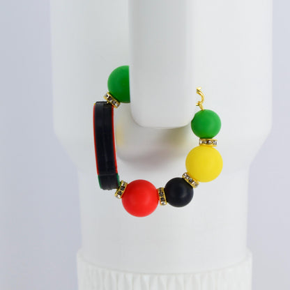 A colorful handle bracelet with a gold-colored hook. The bracelet features a combination of green, yellow, red, and black beads, accented with gold-colored rhinestone spacers. A black and red rectangular element is also included.