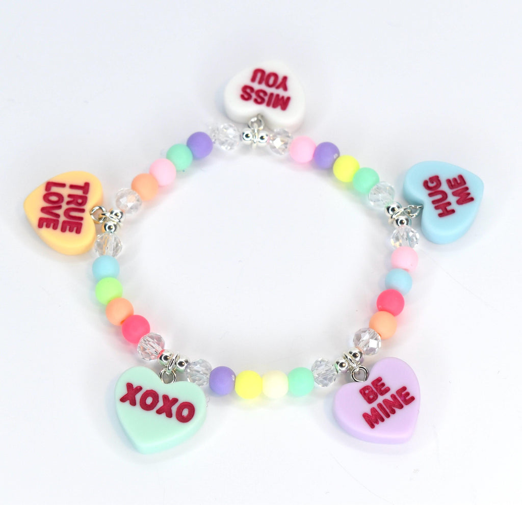 A colorful beaded bracelet with heart-shaped charms. The charms have messages like "TRUE LOVE," "MISS YOU," "HUG ME," "BE MINE," and "XOXO." The beads are pastel colors, and the bracelet has silver-colored accents.