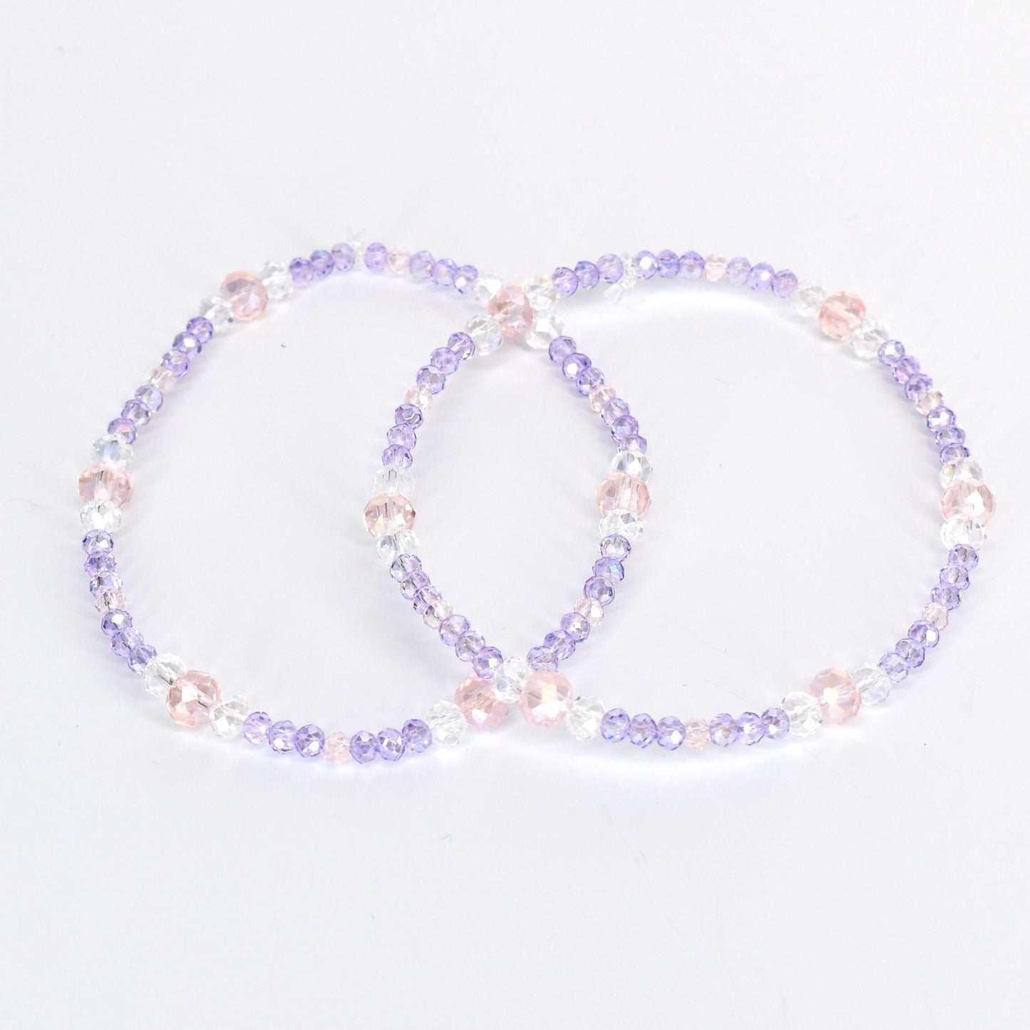 Two beaded bracelets. Each bracelet is a circle of small, light purple, clear, and pink beads. The bracelets are on a white background. The beads are strung together with a clear string.