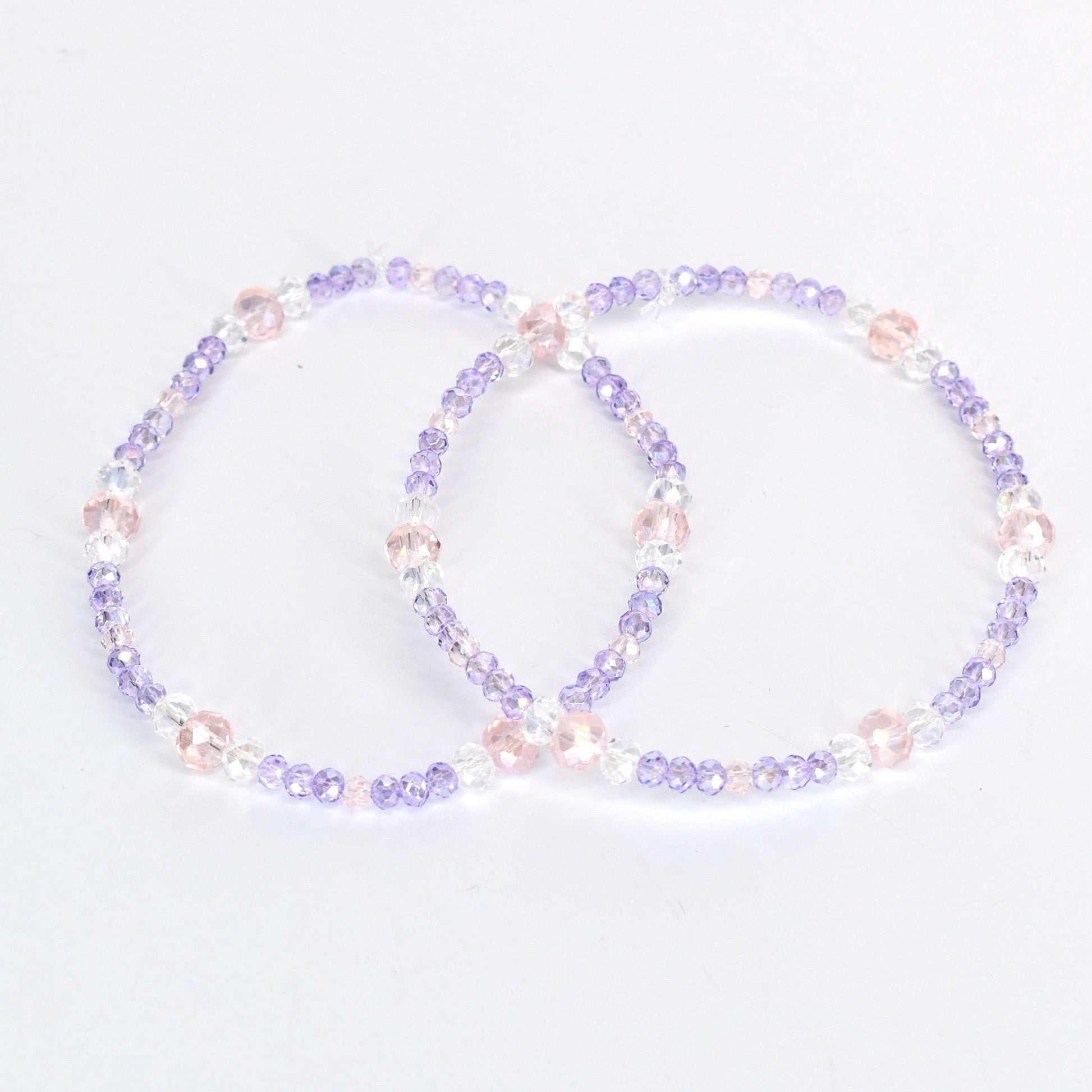 Two beaded bracelets. Each bracelet is a circle of small, light purple, clear, and pink beads. The bracelets are on a white background. The beads are strung together with a clear string.