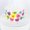 A white silicone tumbler boot decorated with colorful candy heart graphics. The hearts feature phrases like "Be Mine," "Kiss Me," and "Soul Mate." The tumbler boot is on a white surface.
