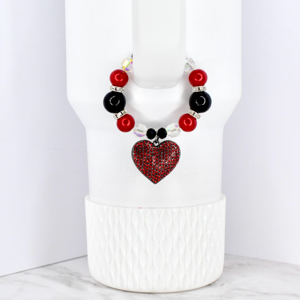 A beaded cup charm featuring red, black, and clear beads. A red heart-shaped charm with a rhinestone design hangs from the beads. The charm is designed to fit around a cup or tumbler.