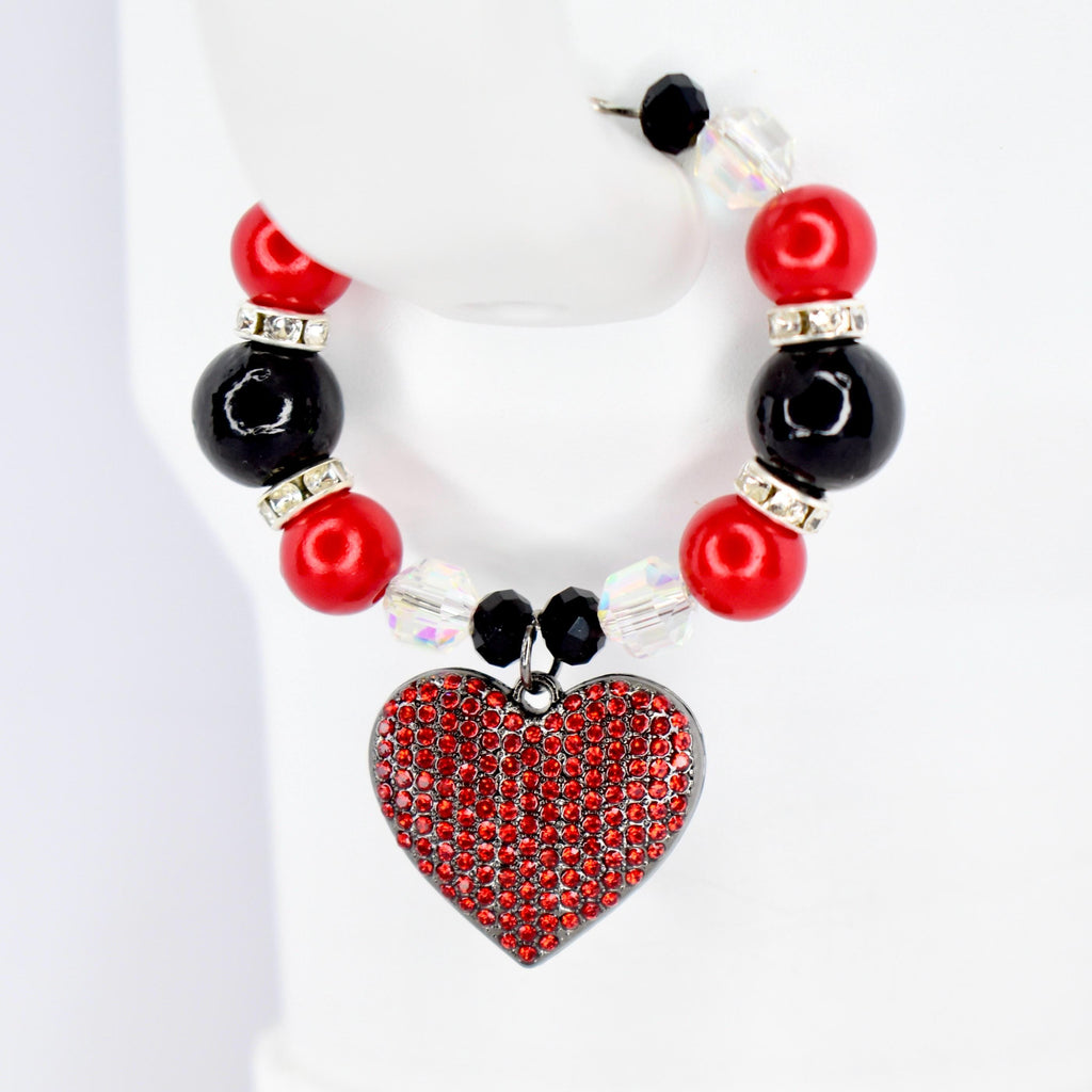 A beaded Stanley handle bracelet featuring red and black beads, clear crystal beads, and a heart-shaped pendant. The heart pendant is covered in small red rhinestones. The bracelet is displayed on a white surface.