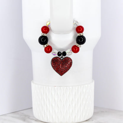 A beaded cup charm with a red heart pendant. The charm features red and black beads, clear crystal accents, and a heart-shaped pendant covered in red rhinestones. The charm is designed to fit around a cup.
