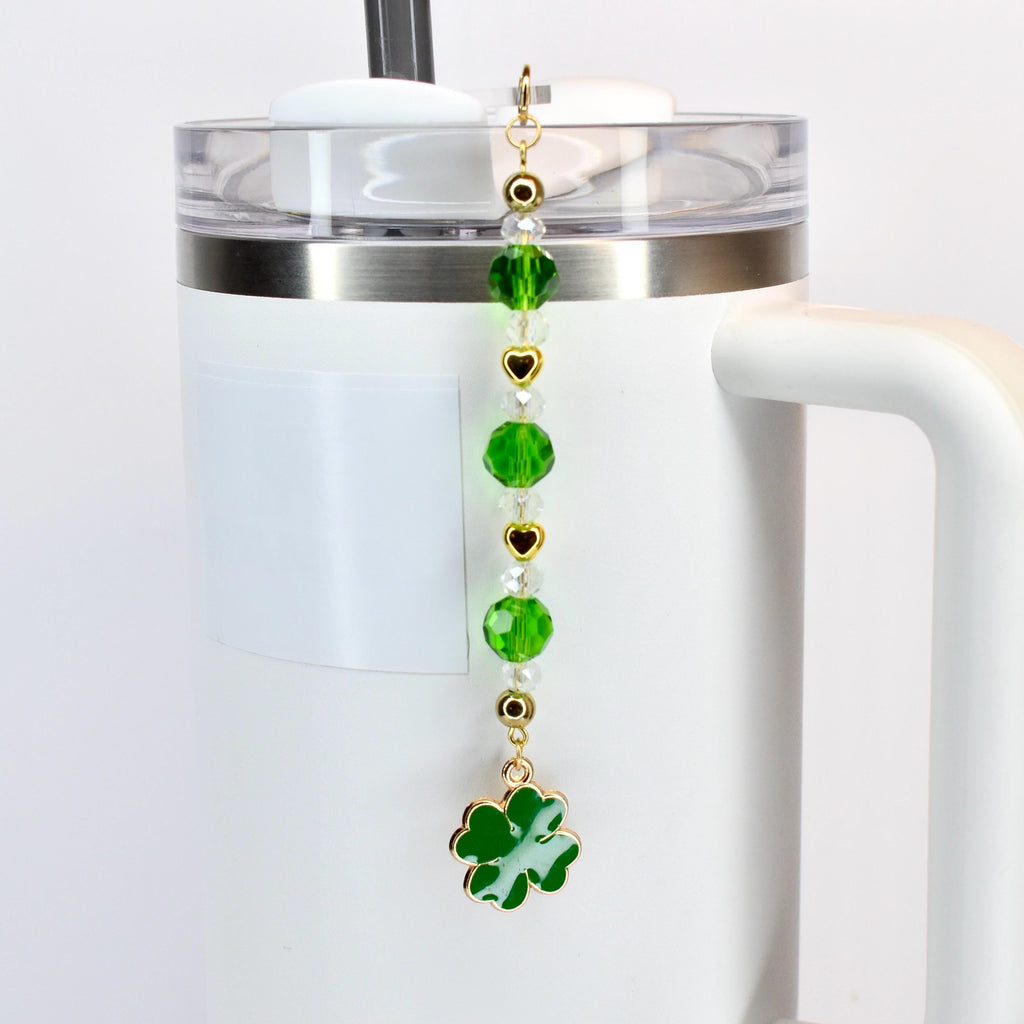 A St. Patrick's Day themed charm for a tumbler. The charm features a gold-colored chain with green beads, clear beads, and gold heart-shaped accents. A green enamel four-leaf clover charm dangles at the bottom.