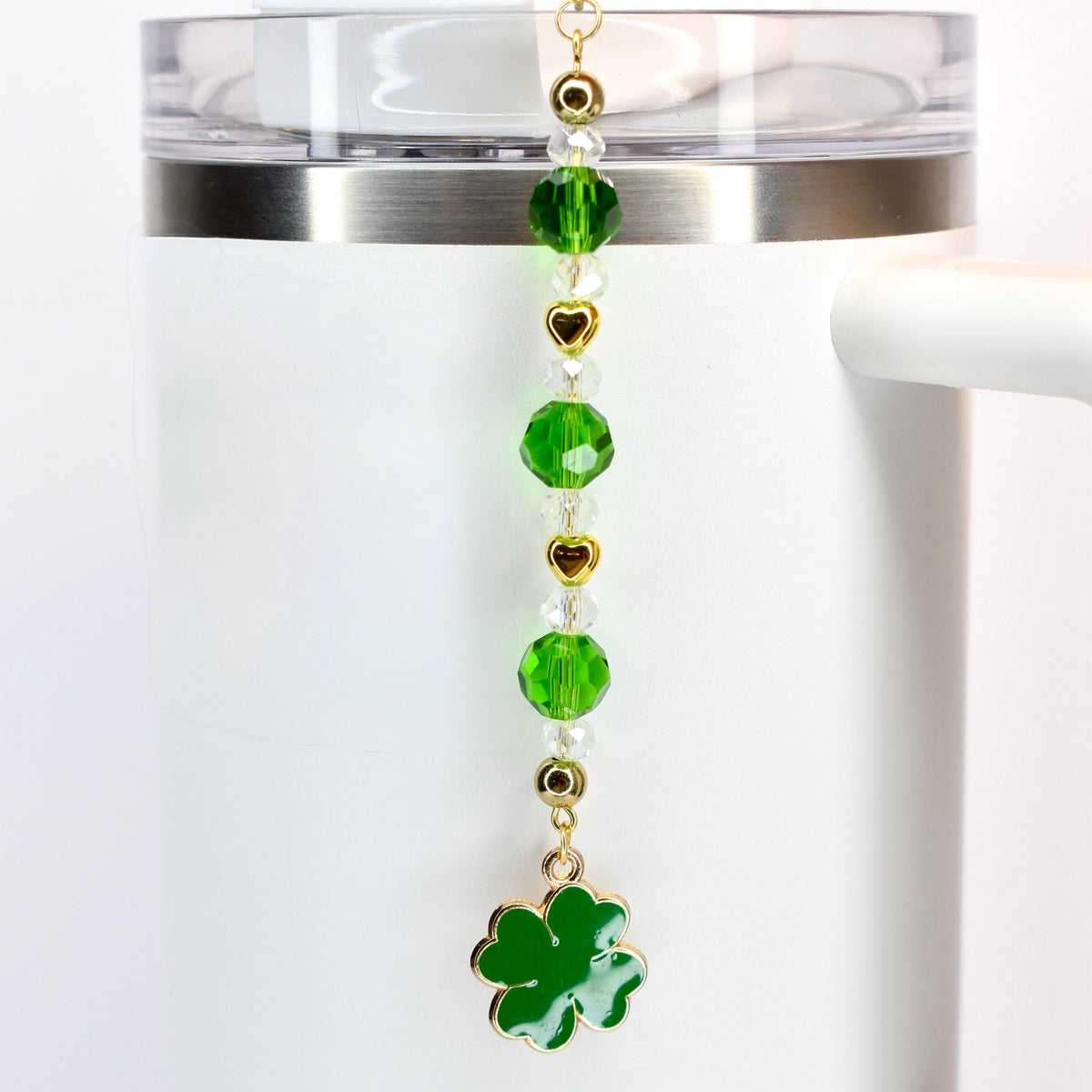 A green, crystal and gold beaded tumbler straw charm with a green shamrock charm at the bottom.