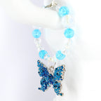 A blue and silver butterfly charm tumbler handle bracelet. The tumbler bracelet features a detailed, ornate butterfly pendant with blue accents and clear and blue beaded accents. The bracelet is held up against a white background.