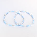 Two light blue beaded bracelets with clear crystal accents and silver-toned metal beads. The bracelets are displayed on a white background. The bracelets are delicate and elegant.