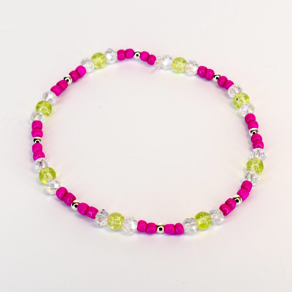 A beaded bracelet featuring a vibrant color scheme. The bracelet alternates between bright pink beads, clear crystal-like beads, and light green beads. Small silver-colored beads are interspersed throughout the design. The bracelet is designed to be worn around the wrist.