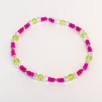 A beaded bracelet featuring a vibrant color scheme. The bracelet alternates between bright pink beads, clear crystal-like beads, and light green beads. Small silver-colored beads are interspersed throughout the design. The bracelet is designed to be worn around the wrist.