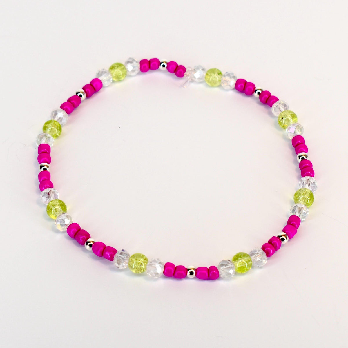 A beaded bracelet featuring a vibrant color scheme. The bracelet alternates between bright pink beads, clear crystal-like beads, and light green beads. Small silver-colored beads are interspersed throughout the design. The bracelet is designed to be worn around the wrist.
