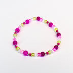 A beaded bracelet featuring a mix of vibrant colors. The bracelet includes large, round magenta beads, interspersed with smaller, clear, and light green beads. The beads are strung together with a silver-colored string, creating a colorful accessory.