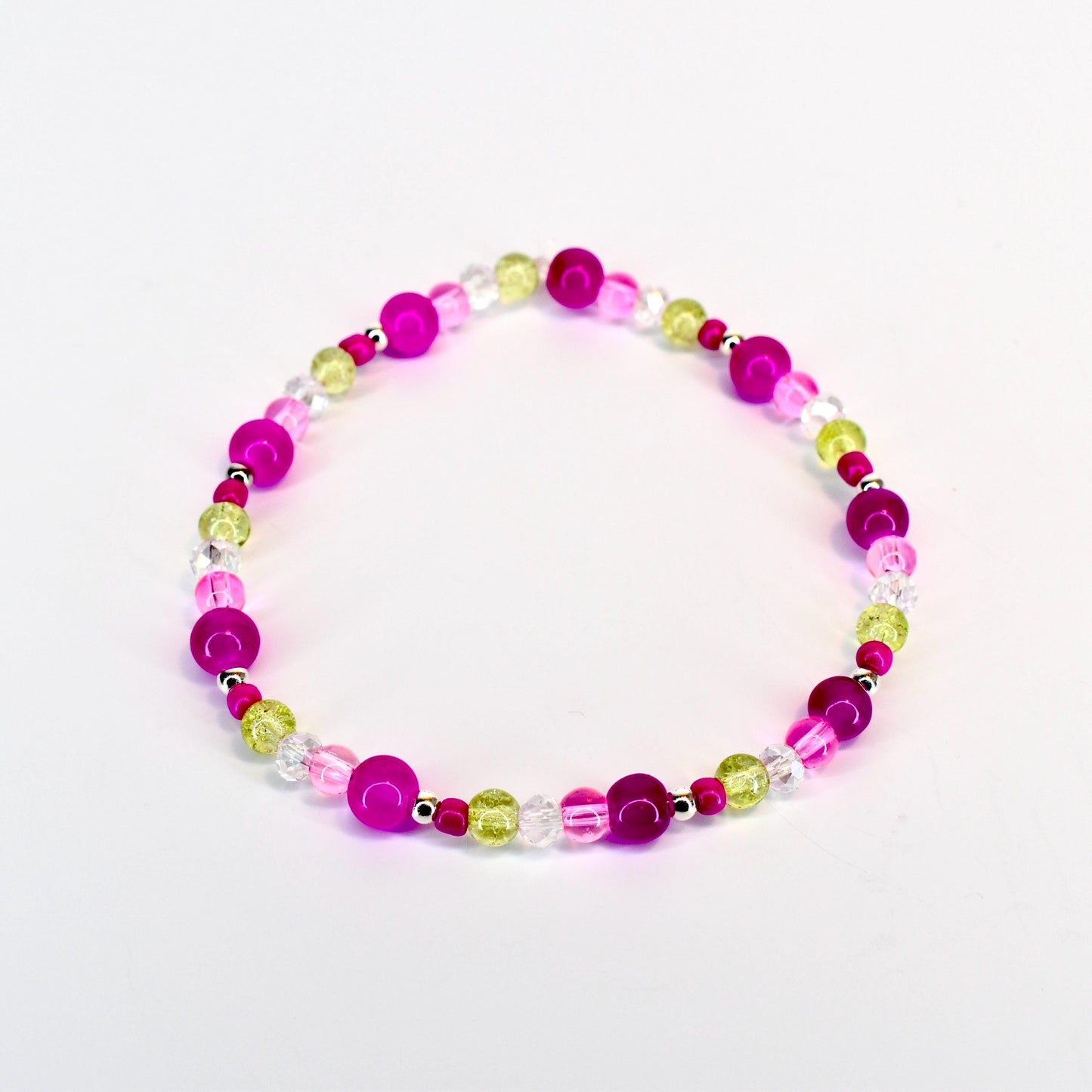 A beaded bracelet featuring a mix of vibrant colors. The bracelet includes large, round magenta beads, interspersed with smaller, clear, and light green beads. The beads are strung together with a silver-colored string, creating a colorful accessory.