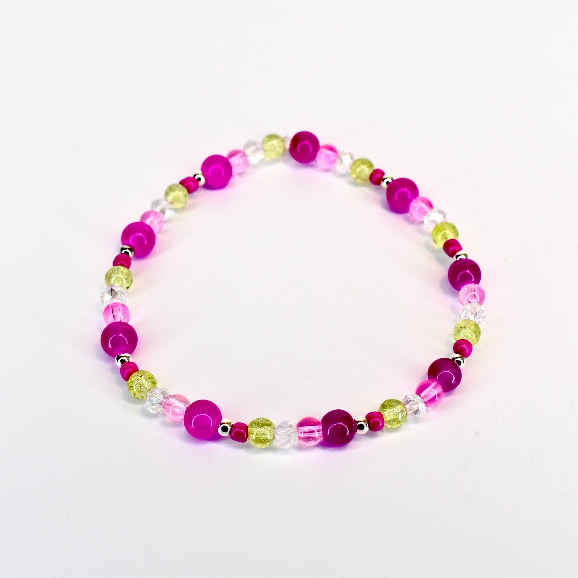 A beaded bracelet featuring a mix of vibrant colors. The bracelet includes large, round magenta beads, interspersed with smaller, clear, and light green beads. The beads are strung together with a silver-colored string, creating a colorful accessory.