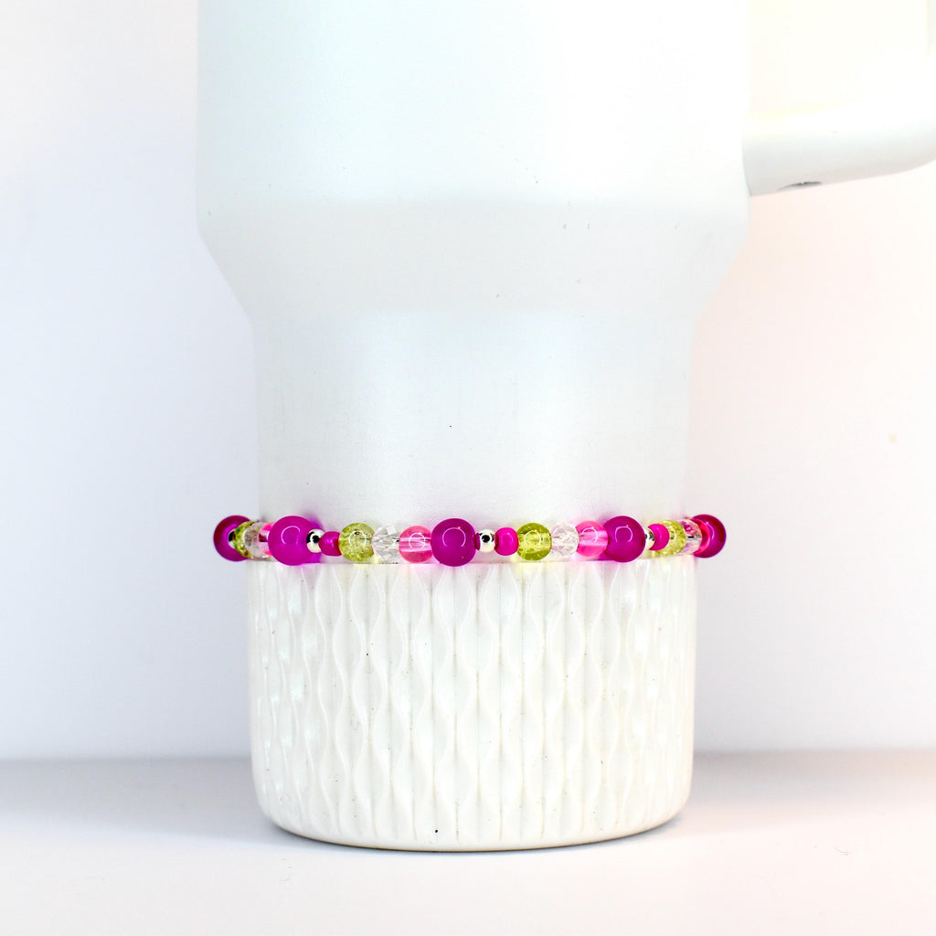A beaded bracelet featuring a mix of vibrant colors. The bracelet showcases a combination of bright pink, clear, and light green beads. The beads are strung together, creating a colorful and eye-catching accessory.
