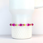 A beaded bracelet featuring a mix of vibrant colors. The bracelet showcases a combination of bright pink, clear, and light green beads. The beads are strung together, creating a colorful and eye-catching accessory.