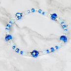 A beaded bracelet featuring a mix of blue and white beads. The bracelet has large, faceted blue beads interspersed with smaller, round white and blue beads. Silver-toned spacers add detail.