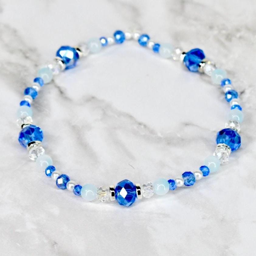 A beaded bracelet featuring a mix of blue and white beads. The bracelet has large, faceted blue beads interspersed with smaller, round white and blue beads. Silver-toned spacers add detail.