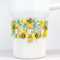 A set of five yellow and mint beaded bracelets with a daisy charm and gold bee beaded accents.
