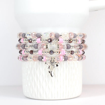 Stack of beaded bracelets in shades of pink, plum purple, and clear. Each bracelet features a mix of beads, including round, faceted, and spacer beads. A silver-tone bow charm hangs from the bottom bracelet. The bracelets are displayed on a white ceramic container.