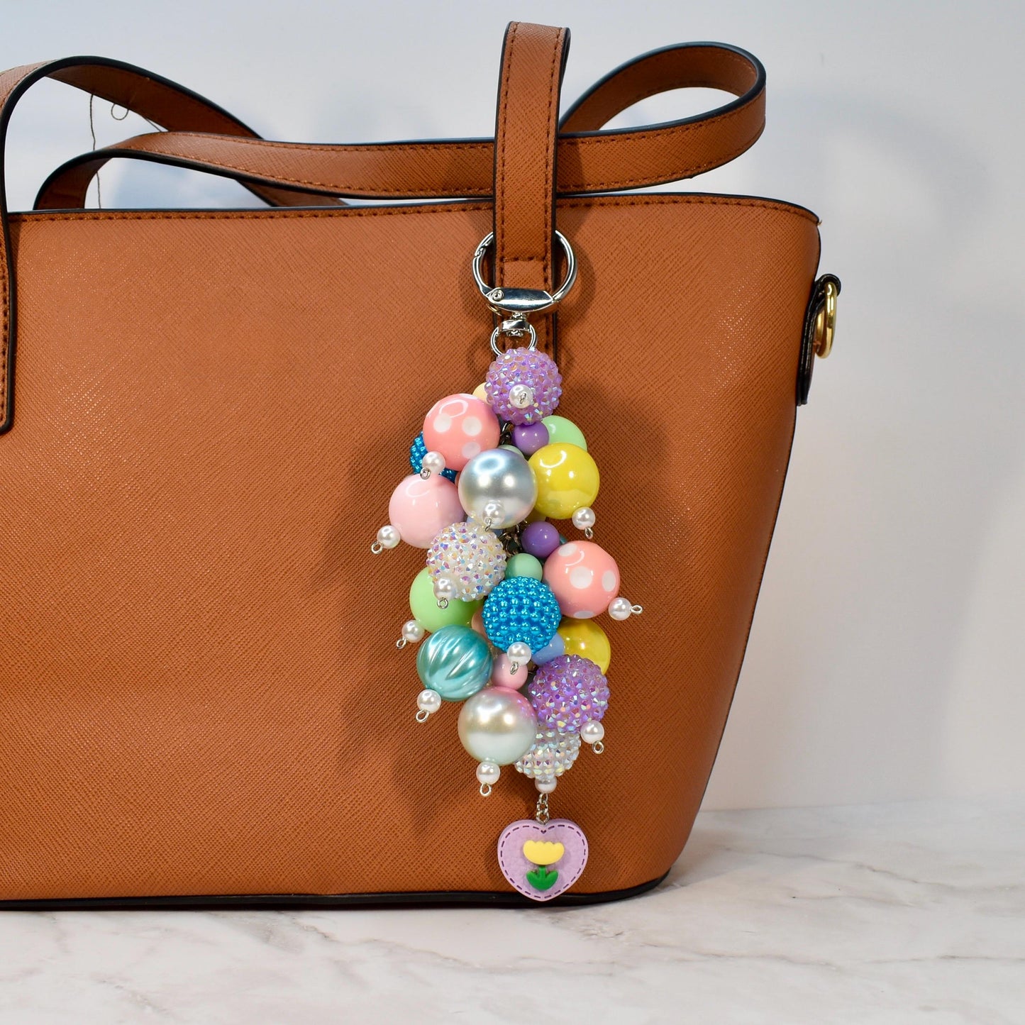 Handmade pastel spring bag charm showcasing a vibrant mix of glossy, rhinestone, and pearl beads with a sweet heart flower charm at the base. Cheerful colorful beaded purse accessory and statement keychain for spring style lovers.