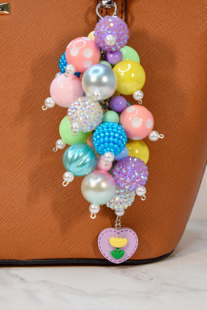 Colorful pastel beaded purse charm featuring mixed glossy and textured beads with pearl details and floral heart pendant. Handmade bag charm and keychain accessory, perfect as a spring gift, Easter accessory, or cute handbag charm.