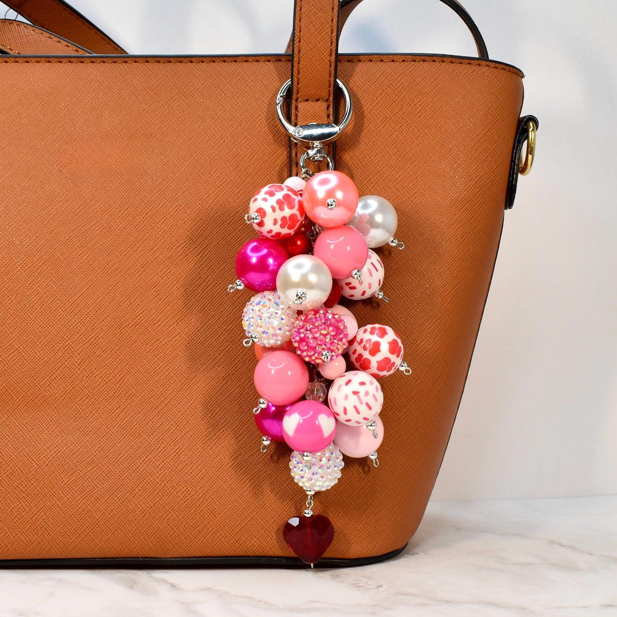 Handmade pink beaded purse charm featuring heart-pattern beads, pearls, rhinestone accents, and a dangling heart charm. Romantic Valentine bag charm and statement keychain, ideal as a Valentine’s Day gift or cute handbag accessory.