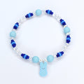 A bracelet with pastel blue and blue gradient heishi beads with crystal and pearl accent beads. A pastel blue PEEPS charm is the focal point of the bracelet.
