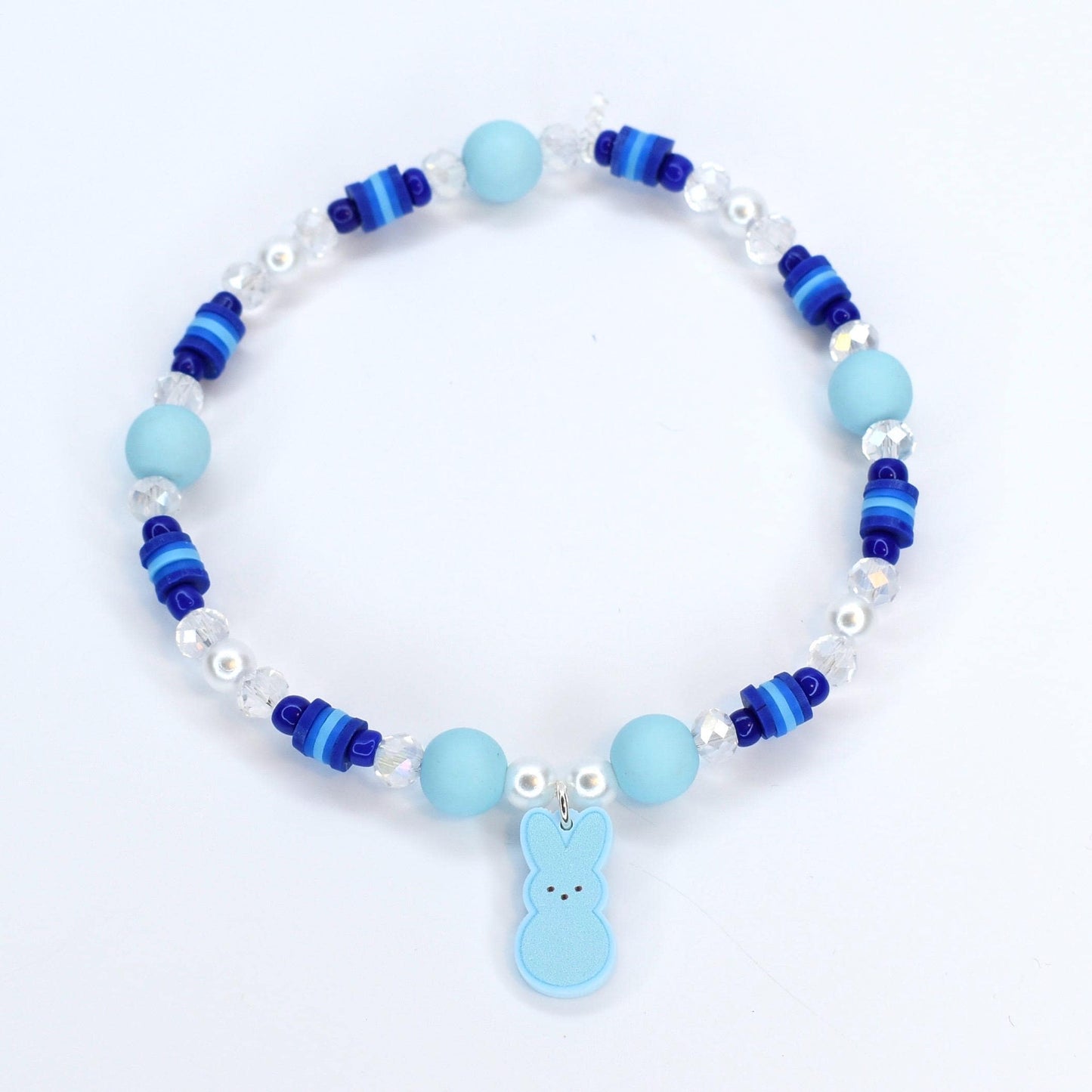 A bracelet with pastel blue and blue gradient heishi beads with crystal and pearl accent beads. A pastel blue PEEPS charm is the focal point of the bracelet.