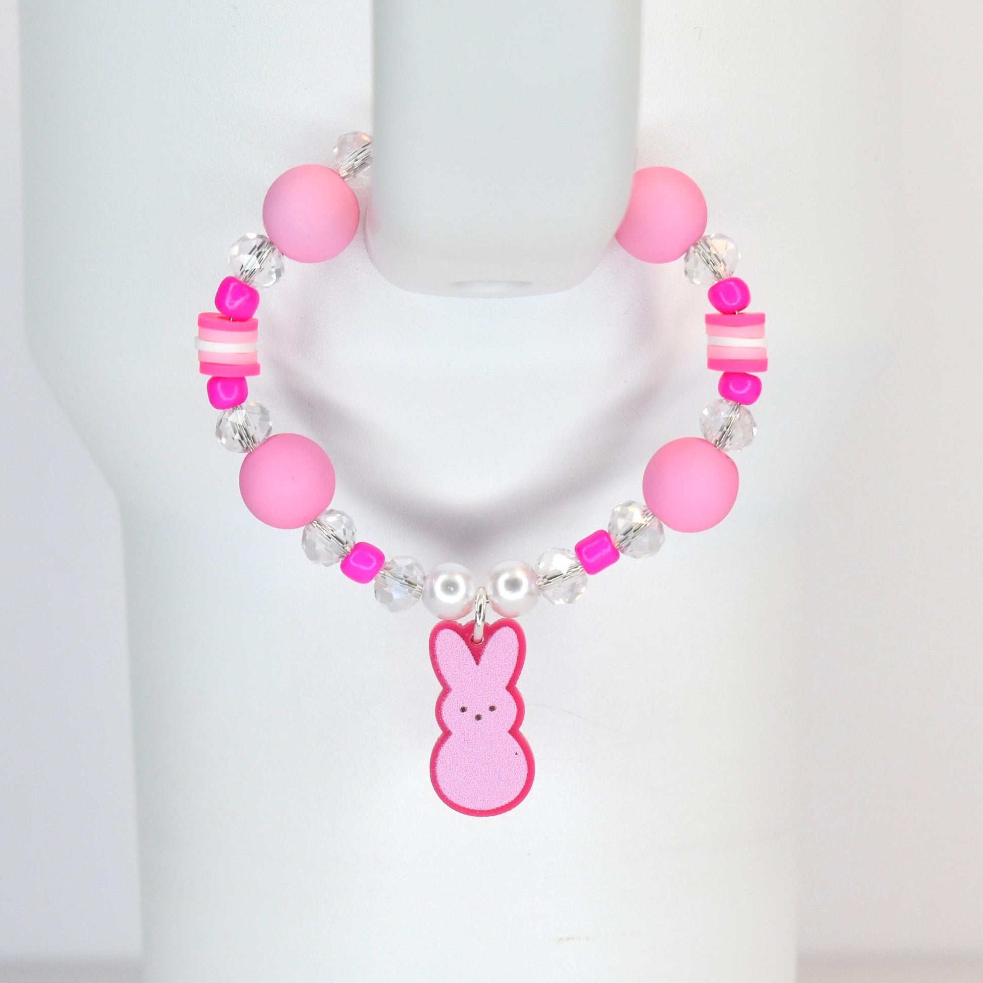 A pink beaded tumbler handle bracelet with a Peep-shaped charm. The bracelet features large pink beads, clear crystal beads, and small pink and white accent beads. The charm is a pink bunny with a pink outline.