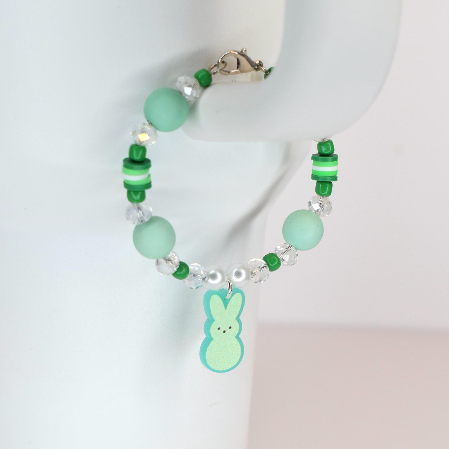 A beaded bracelet with a light green Peep charm. The bracelet features light green and clear beads, with a silver clasp. The bracelet is a spring-themed accessory.
