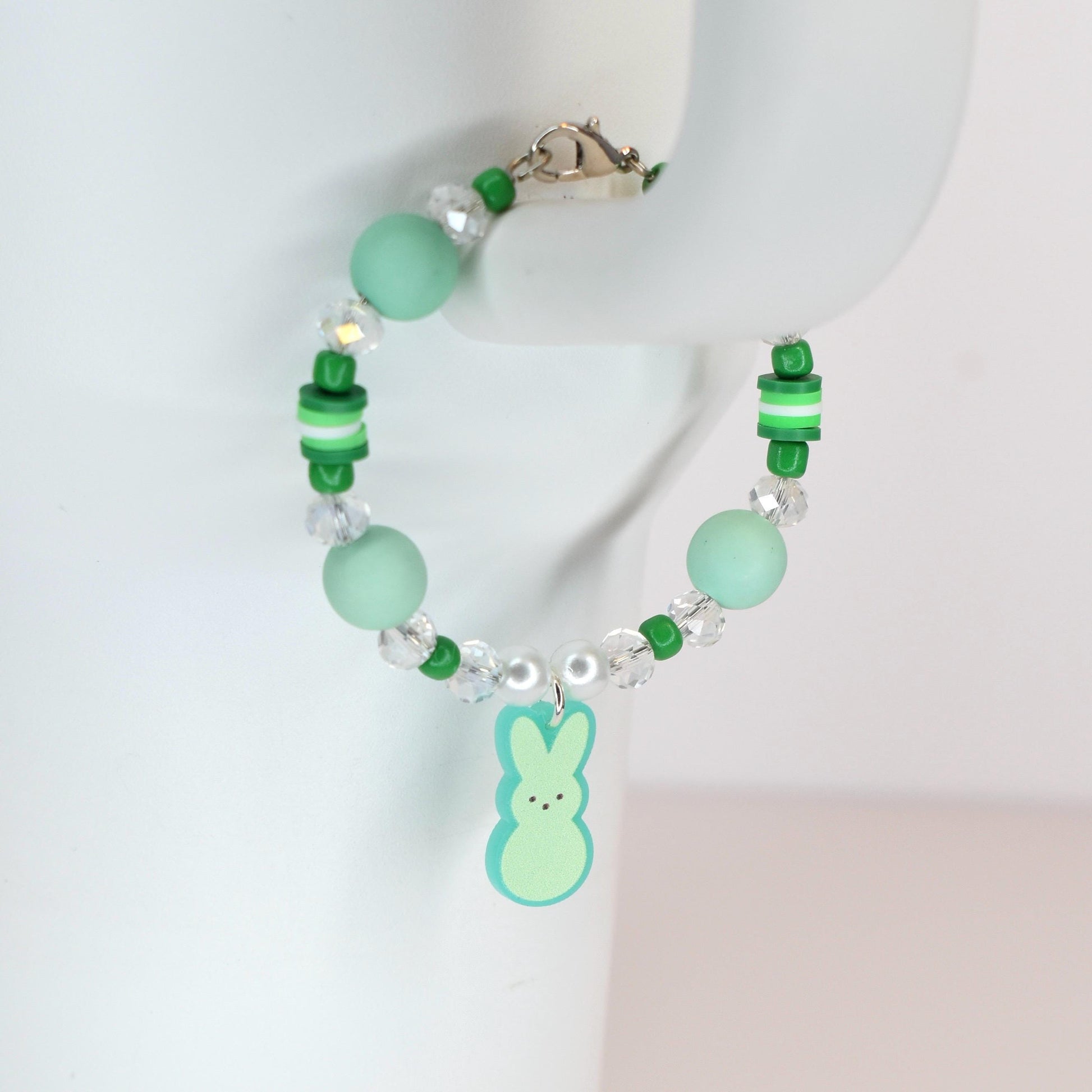 A beaded bracelet with a light green Peep charm. The bracelet features light green and clear beads, with a silver clasp. The bracelet is a spring-themed accessory.